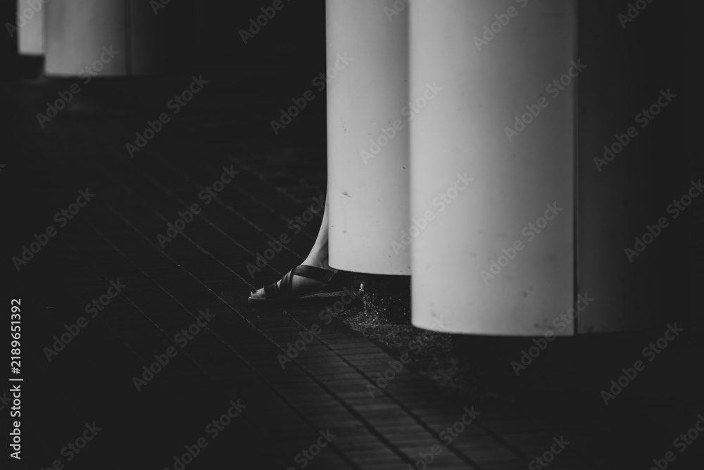 Obraz premium Black and white architectural column beside tiled pavement creates stark urban scene with dramatic shadow, texture, and minimalist geometric composition