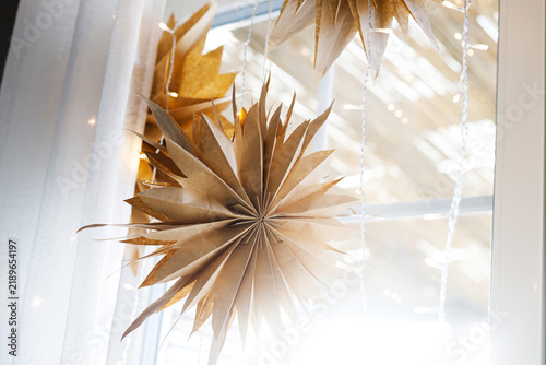 Handcrafted Paper Stars Hanging in Window with Warm Fairy Lights, Concept of Nordic Christmas Decor, Eco-Friendly Winter Interior and Cozy Lighting