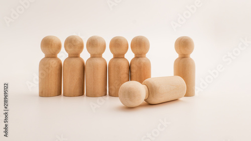Bild auf Leinwand Wooden peg figures represent a team with one member fallen down
