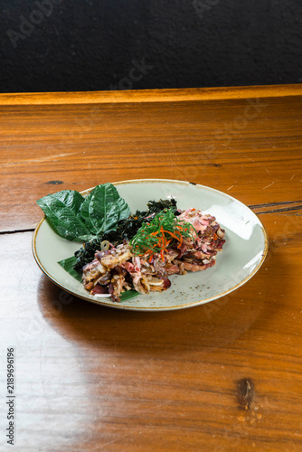 Gourmet Dish: A beautifully plated gourmet dish features tender meat with exotic spices and garnishes, served on a rustic wooden table.
