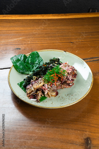 Savory Seafood Delight: A delectable seafood dish, artfully presented with vibrant green leaves, rests on a rustic wooden table, promising a culinary adventure.