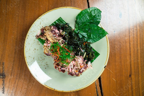 Exotic Delicacy on a Plate: A meticulously prepared dish, featuring a unique blend of ingredients, rests on a pale green plate, artfully garnished with fresh green leaves.