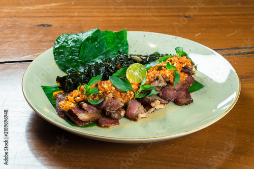 Smoked Beef with Sambal and Leafy Greens: A gourmet dish of thinly sliced smoked beef, topped with a vibrant sambal and garnished with lime.
