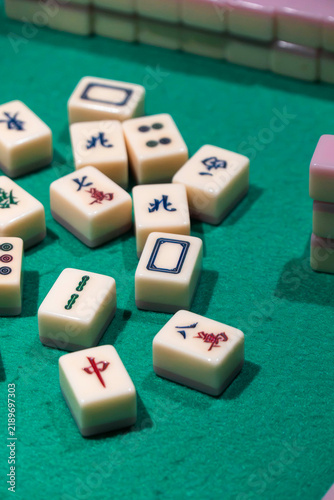 Mahjong Tiles on Felt Surface: A collection of classic mahjong tiles scattered on a green felt surface, showcasing intricate symbols and numbers for this traditional game.