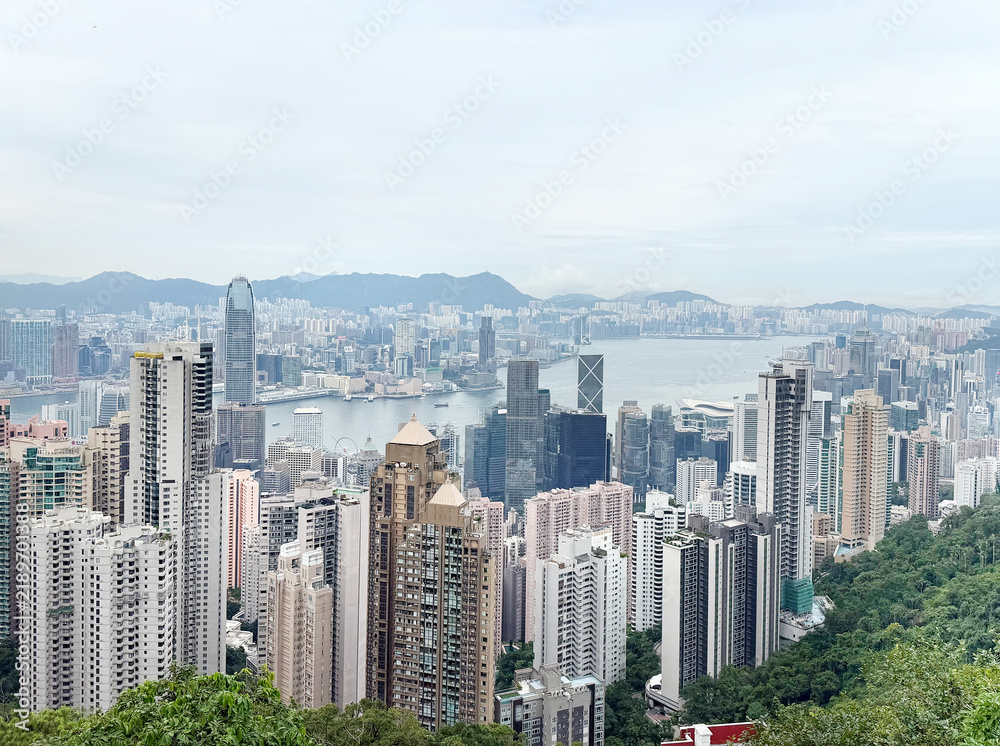 Obraz premium Panoramic view of Hong Kong skyline with skyscrapers and green hillsides on display. 