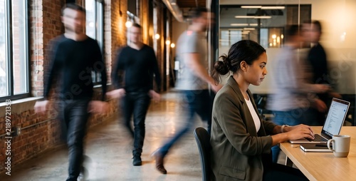Woman Working on Laptop in Busy Modern Office