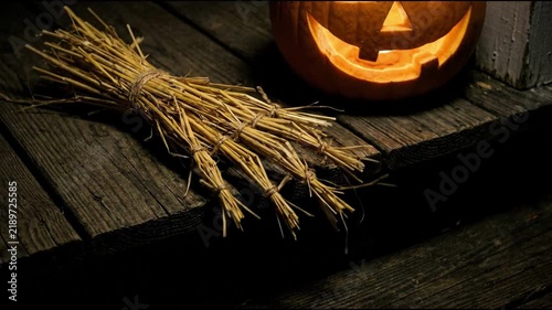 Atmospheric halloween scene featuring a glowing jack o lantern and a bundle of straw on rustic wooden porch steps during a dark spooky autumn night