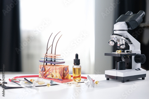Konstfotografi Scalp anatomy model with hair follicles and dropper oil bottle beside microscope