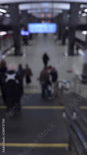Defocused commuters descending an escalator in a subway station, illustrating public transport, daily commute, urban mobility and busy city life