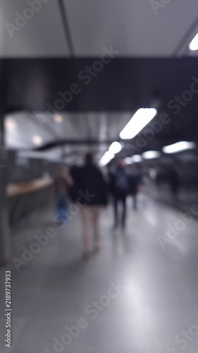 Defocused commuters walking through a modern subway station, illustrating public transit, urban mobility, daily commute and fast paced city life