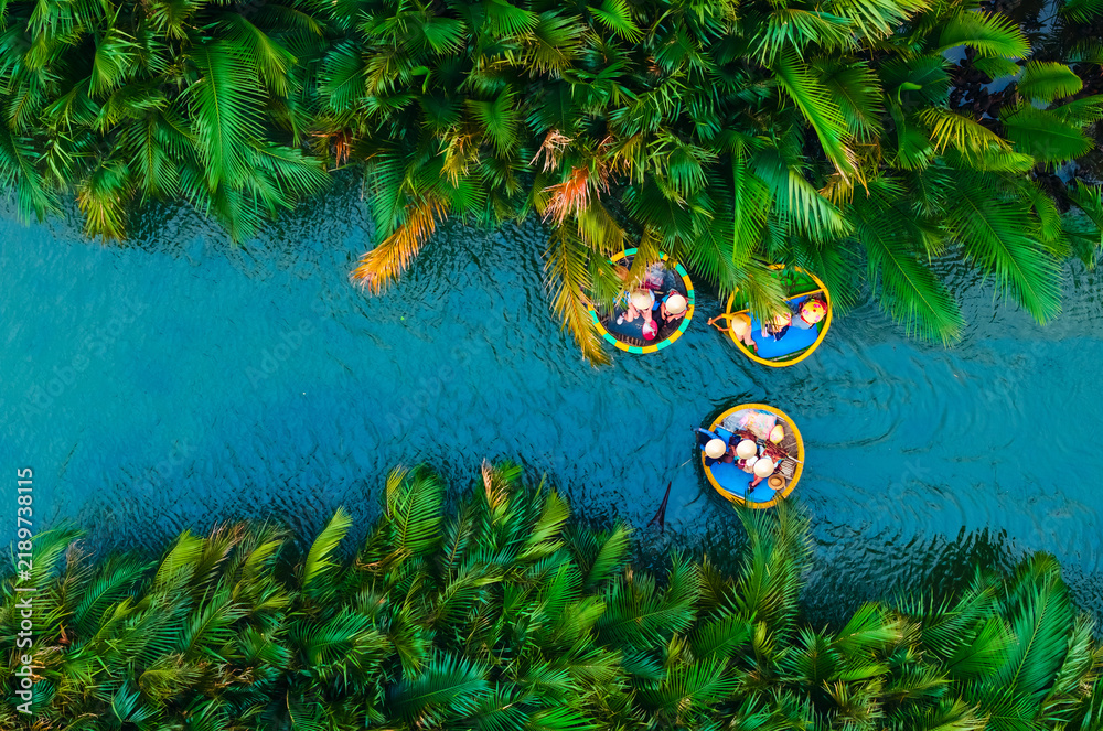 Obraz premium Aerial view of basket boats navigating lush waterways in hoi an, vietnam