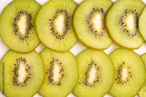 Foto Fresh kiwifruit background closeup with whole kiwi fruit and juicy green slices row texture, healthy organic tropical dessert vitamin food macro pattern, white backdrop horizontal copy space