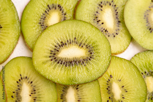 Bild auf Leinwand Fresh kiwifruit background closeup with whole kiwi fruit and juicy green slices row texture, healthy organic tropical dessert vitamin food macro pattern, white backdrop horizontal copy space