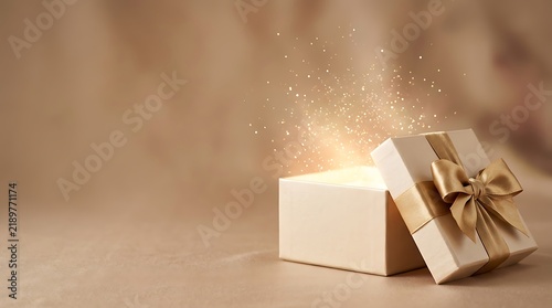 A magical luxury open gift box with golden ribbon glowing with sparkling lights on a soft warm background for special holiday celebration events