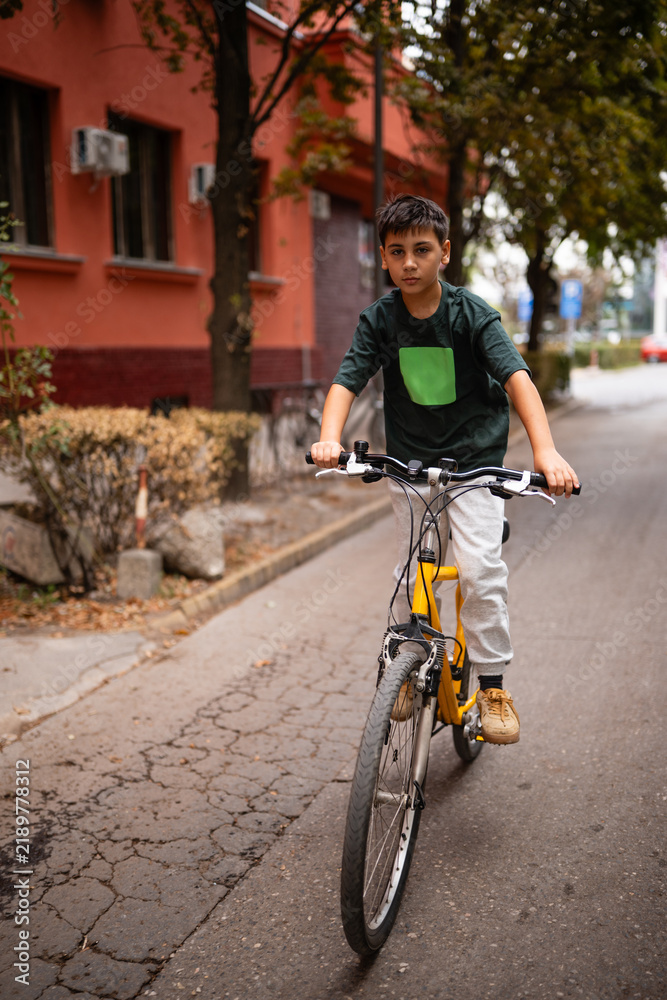 Fototapeta premium Young boy riding bicycle on urban street
