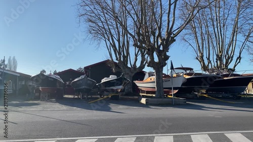 Small boats positioned beside a sidewalk in Arcachon, France, near the coastal waterfront. The scene reflects the town's strong maritime character and connection to Arcachon Bay.