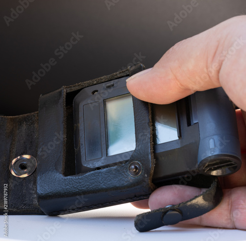 Obraz na płótnie Hand removing an emergency pager from a leather holster close up on white surfac