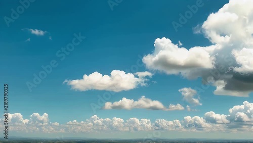Bright 4K cloudscape time-lapse following large fluffy white cumulus clouds as they change shape and sail across a vibrant blue sky ideal for establishing optimistic daytime nature moods