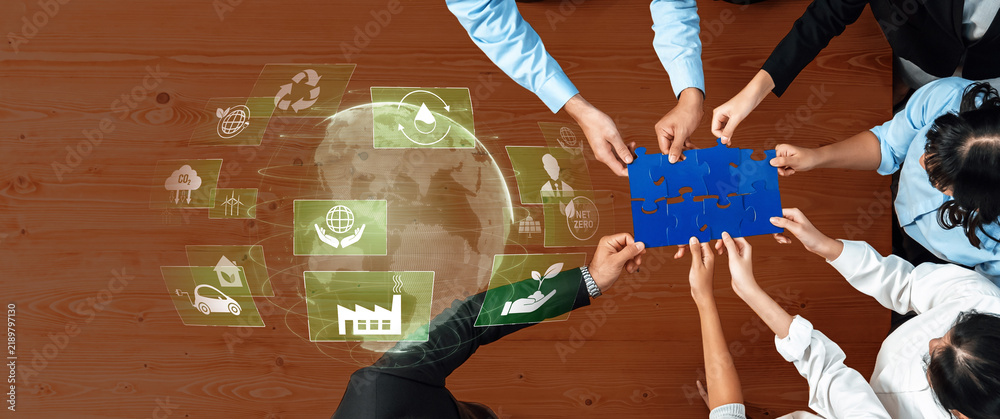 Obraz premium A diverse team collaborates over puzzle pieces, symbolizing commitment to sustainability with digital icons, highlighting eco-friendly practices and innovative solutions. Trope