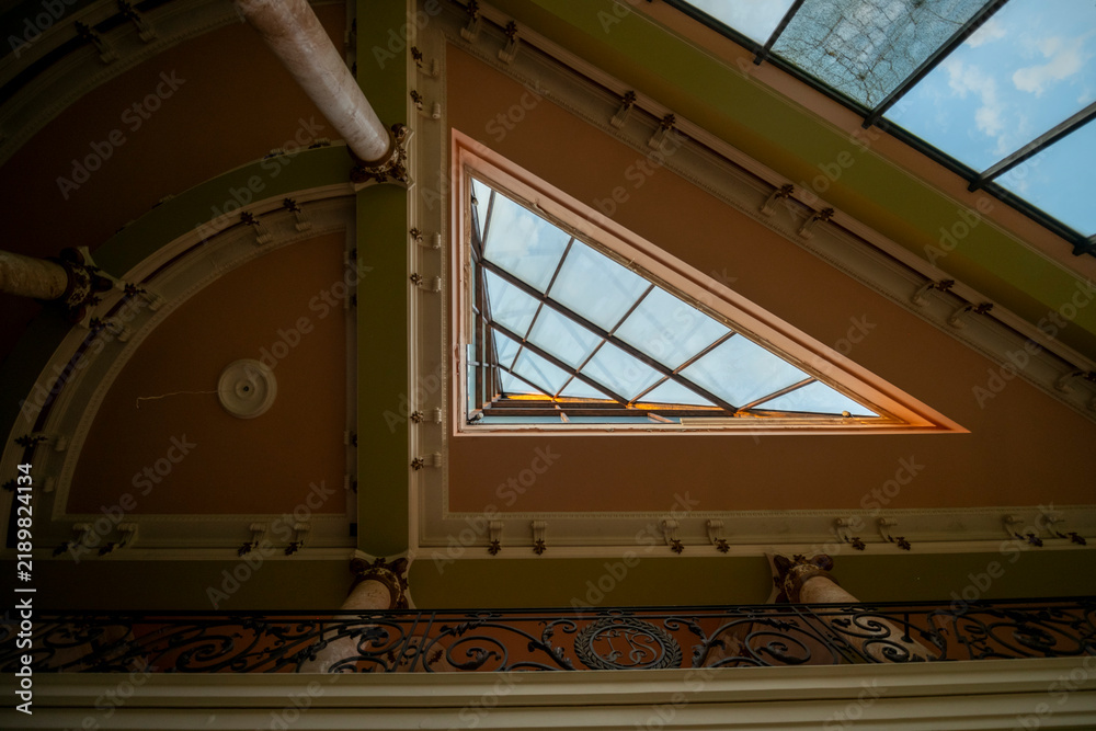 Obraz premium Abandoned luxury mansion interior with marble hall, ornate fireplace, swimming pool and glass facade
