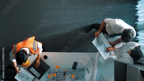 Top down view of smart architect engineer team looking at building design at meeting. Group of diverse designer team working together and discussing about house interior while standing. Alimentation.