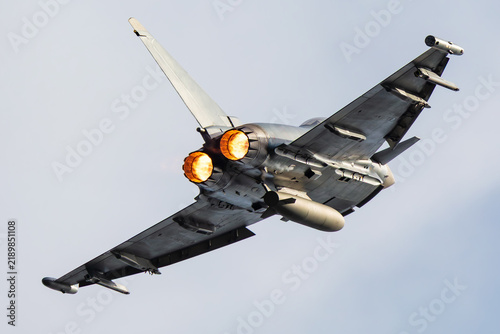 Twin engine fighter jet banking with afterburners