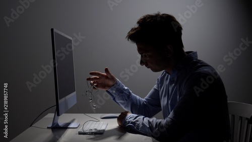 Canvastavla Man holding tangled earphones in frustration while sitting at his computer desk,