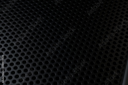  Perforated black metal sheet texture with regular round holes pattern in diagonal perspective. 3D render.