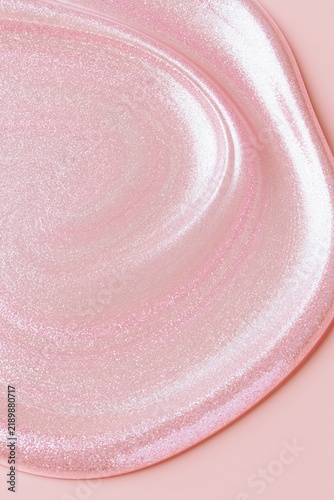 Shimmering pearlescent pink cosmetic gel texture with glossy curved highlights, creating a luxurious abstract beauty background