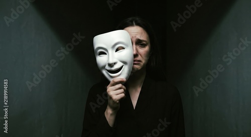 Crying Woman Hiding Face Behind a Smiling Mask