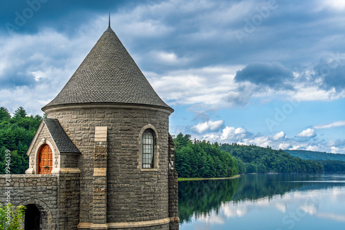 Stone reservoir tower beside a forested mountain lake