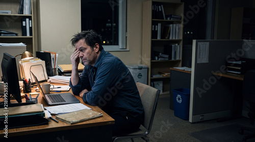 Exhausted Man at Desk in Empty Office