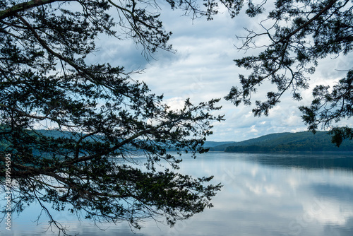 Forest framed lake with mountain shoreline and cloudy sky