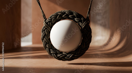 Minimal hanging organic sculpture with white sphere and dark rope