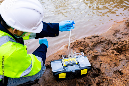 Obraz na plátně Field worker using pipette and test tubes to detect toxic pollutants and heavy metal contamination in river water