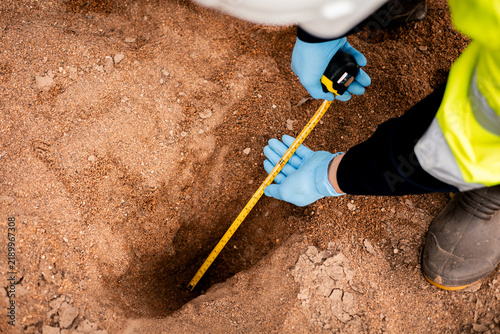 Quadro su tela Environmental technician measuring soil pit depth during sample collection for soil quality analysis