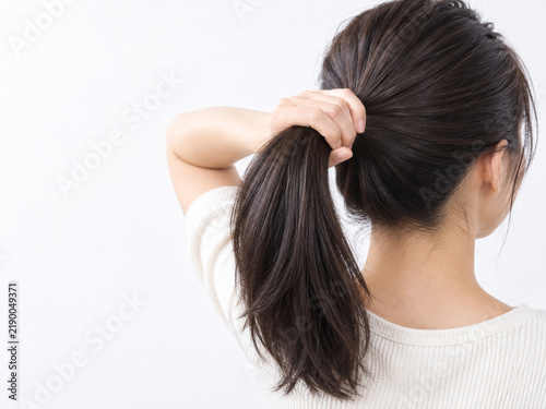 Fototapeta 束ねた髪を握って太さを見せる女性の後ろ姿