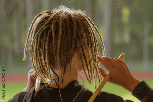 Fotografie Rear view of a percussionist with dreadlocks holding drumsticks during a music p