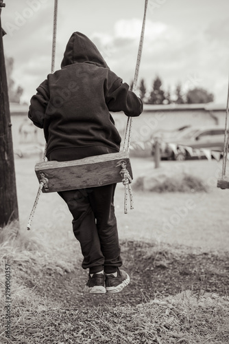 Foto Lonely child on a swing in a somber black and white scene