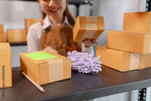 Warehouse employee cleaning storage shelves and organizing parcel boxes to maintain a tidy workspace, improve inventory management, support warehouse hygiene, safety, and daily logistics operations.