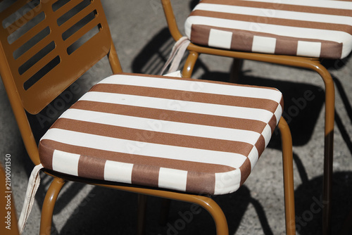 Striped cushions on metal chairs outdoors in a sunny setting