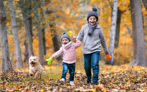 Two Happy Children jumping and running Together through the autumn park