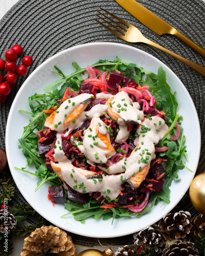 Salmon salad with beetroot, vegetables, and yogurt sauce. Overhead view. Christmas meal with festive decorations.