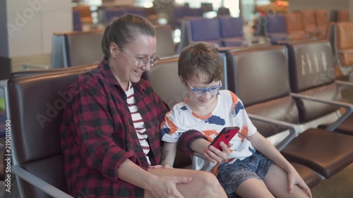 Female passenger and her son are looking photos on smartphone