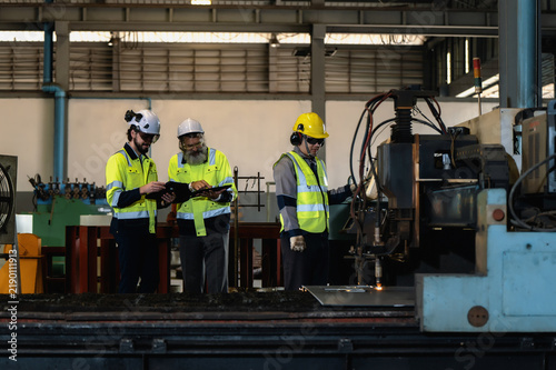 Senior engineer explaining industrial operations to industrial engineer while inspect metal cutting machinery. Concept of smart manufacturing automation, heavy industry quality control audit.