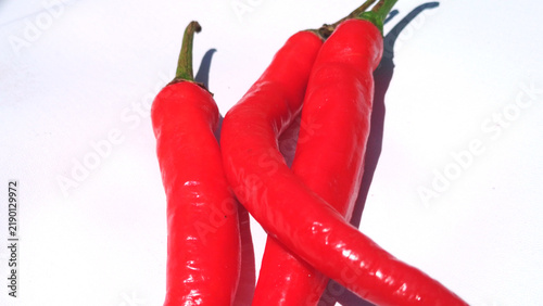 Принти на полотні Fresh Red Chili Peppers with Green Stems on White Background