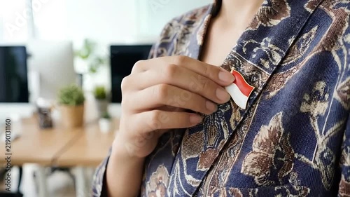 Person Pinning an Indonesian Flag Brooch onto a Traditional Batik Blazer