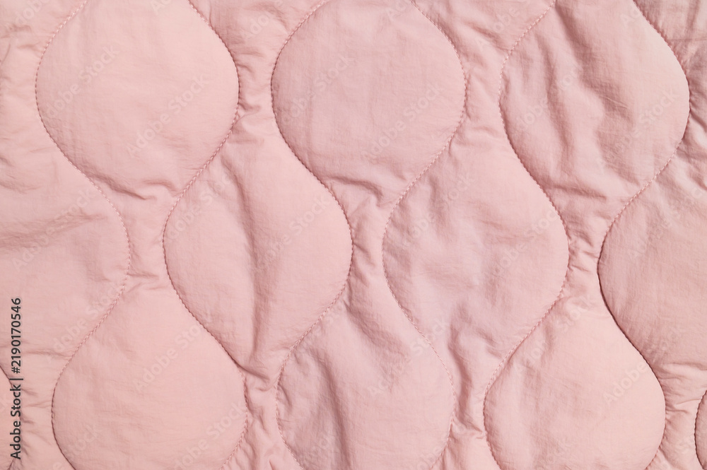 Obraz premium Pink quilted fabric fills closeup frame with stitched organic shapes and soft texture. Textile surface offers gentle material detail for apparel design, bedding concepts and fabric marketing.