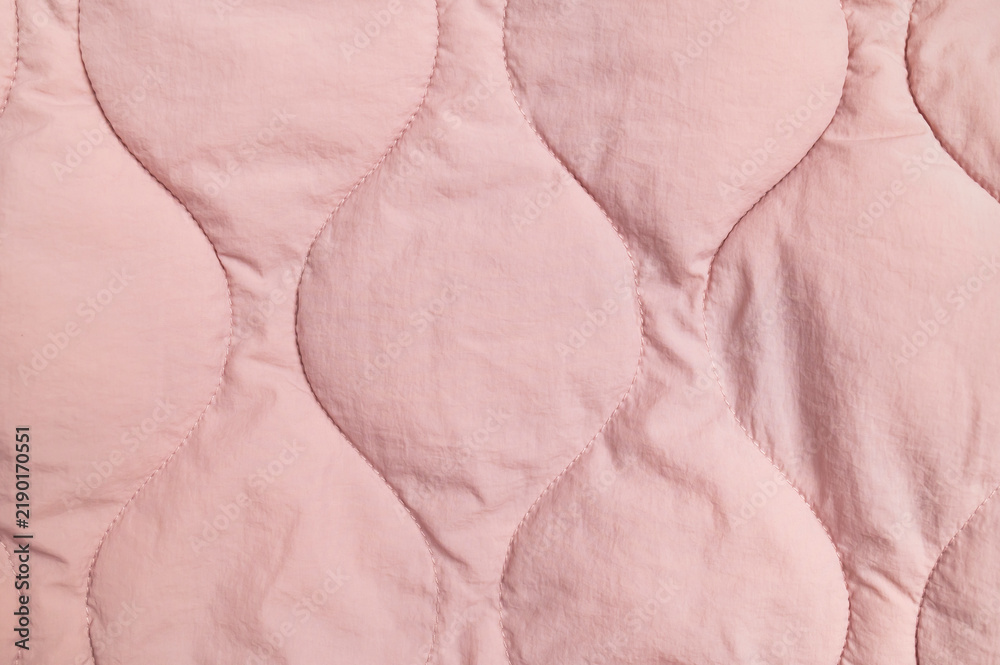 Obraz premium Pink quilted fabric fills closeup frame with stitched organic shapes and soft texture. Textile surface offers gentle material detail for apparel design, bedding concepts and fabric marketing.