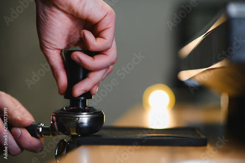 Foto Barista tamping coffee grounds in portafilter for espresso